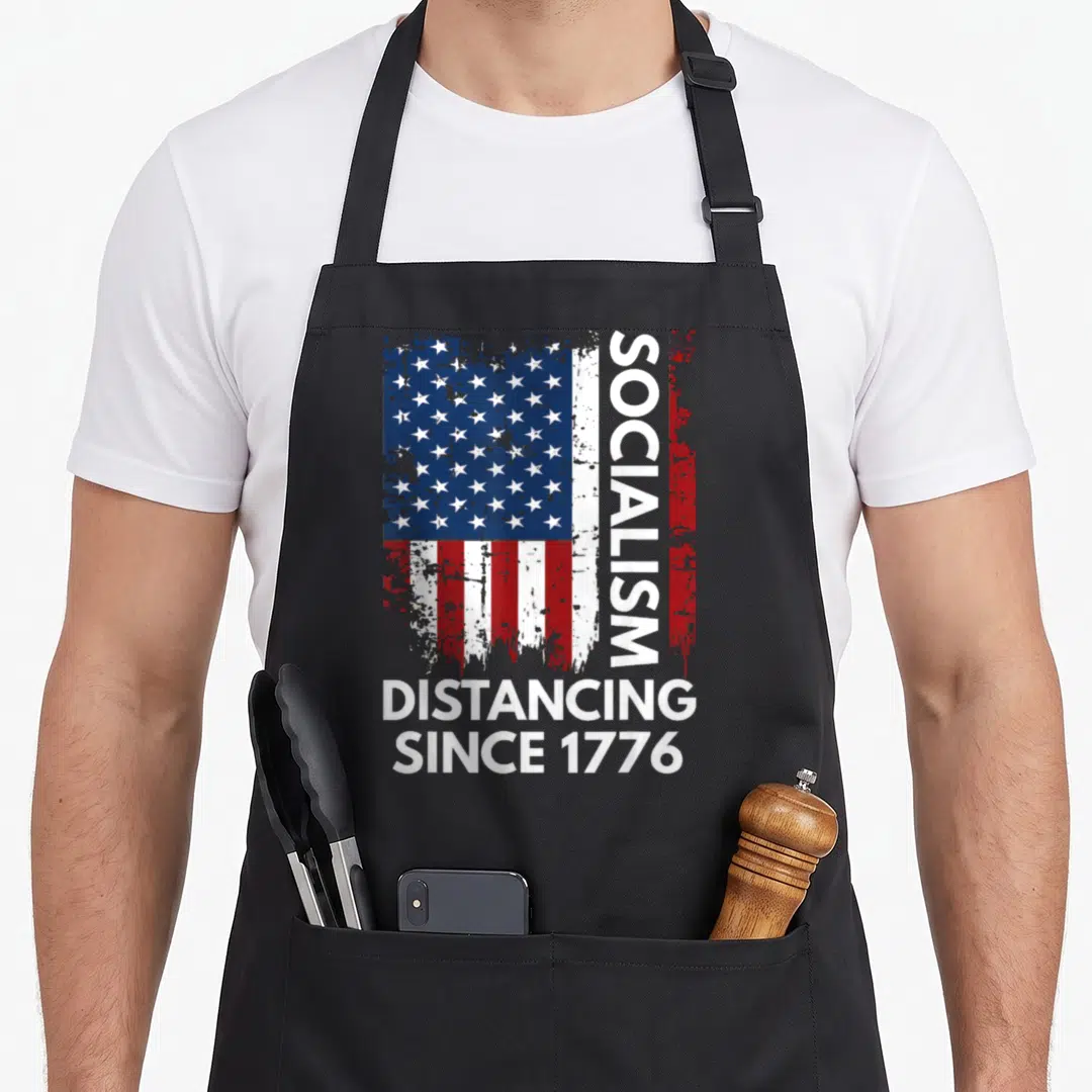 Socialism novelty apron - Distressed USA flag with vertical SOCIALISM text and DISTANCING SINCE 1776 below — shown on a black cotton canvas apron against a white background