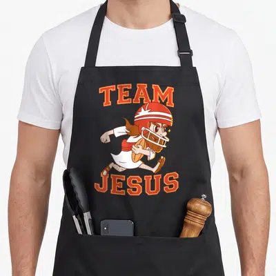 Christian football team aprons - Cartoon Jesus running in helmet holding football with TEAM JESUS text in red — shown on a black cotton canvas apron against a white background