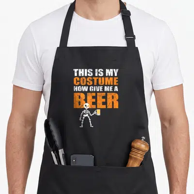 Give halloween apron - Distressed orange and white text above skeleton holding beer mug on black apron — shown on a black cotton canvas apron against a white background
