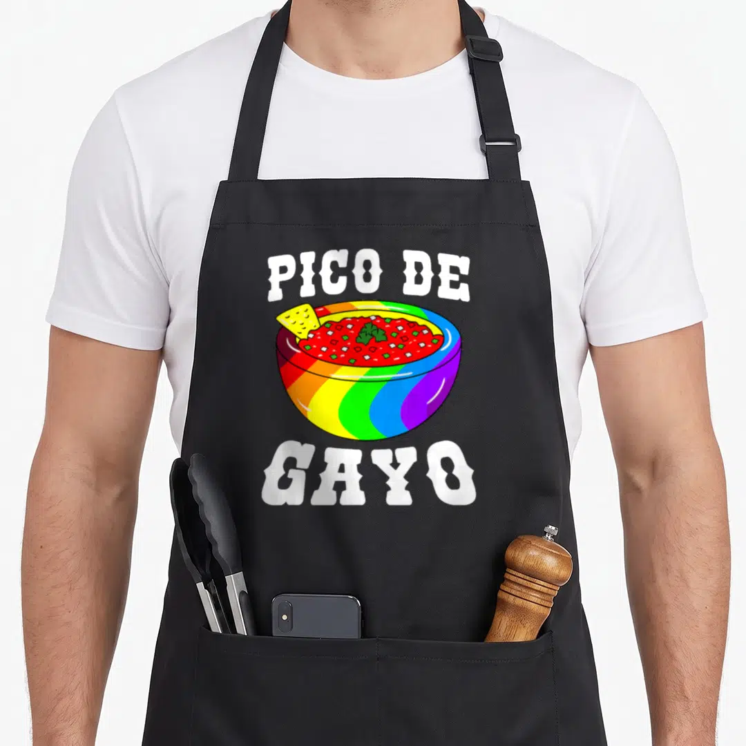 Pico gay pride apron - Cartoon rainbow salsa bowl with PICO DE GAYO text in white block letters — shown on a black cotton canvas apron against a white background