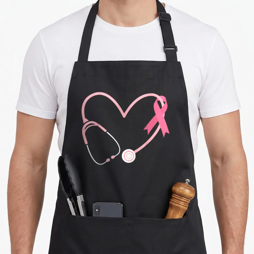 Doctor ribbon apron - Stethoscope heart shape with pink ribbon overlap, minimalist pink and white design — shown on a black cotton canvas apron against a white background