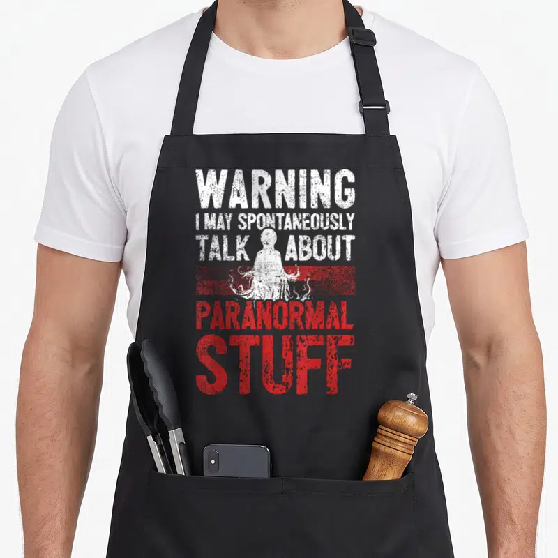 Warning ghost apron - Stacked white and red text surrounding a ghost silhouette behind a red horizontal stripe — shown on a black cotton canvas apron against a white background