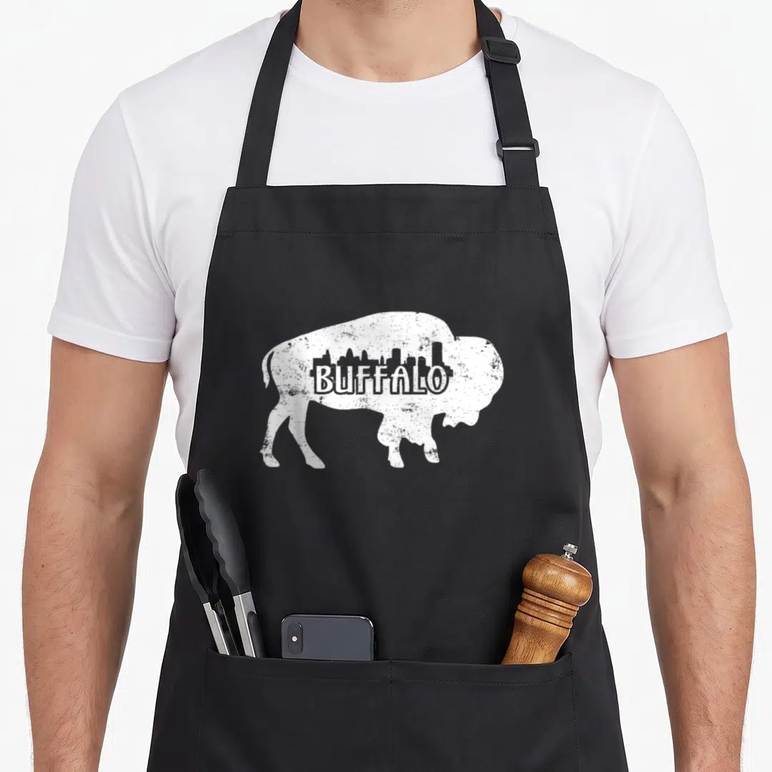 Distressed buffalo apron - White buffalo silhouette with city skyline and text in distressed style — shown on a black cotton canvas apron against a white background