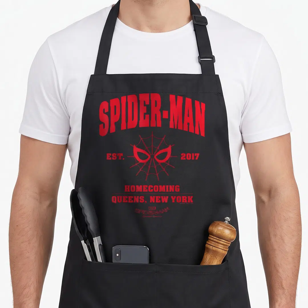 Homecoming collegiate aprons - Red spider web with mask eyes and text reading Spider-Man Est 2017 Queens New York — shown on a black cotton canvas apron against a white background