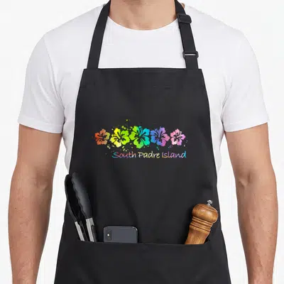 South padres apron - Five rainbow watercolor hibiscus flowers in a row above South Padre Island text on black fabric — shown on a black cotton canvas apron against a white background
