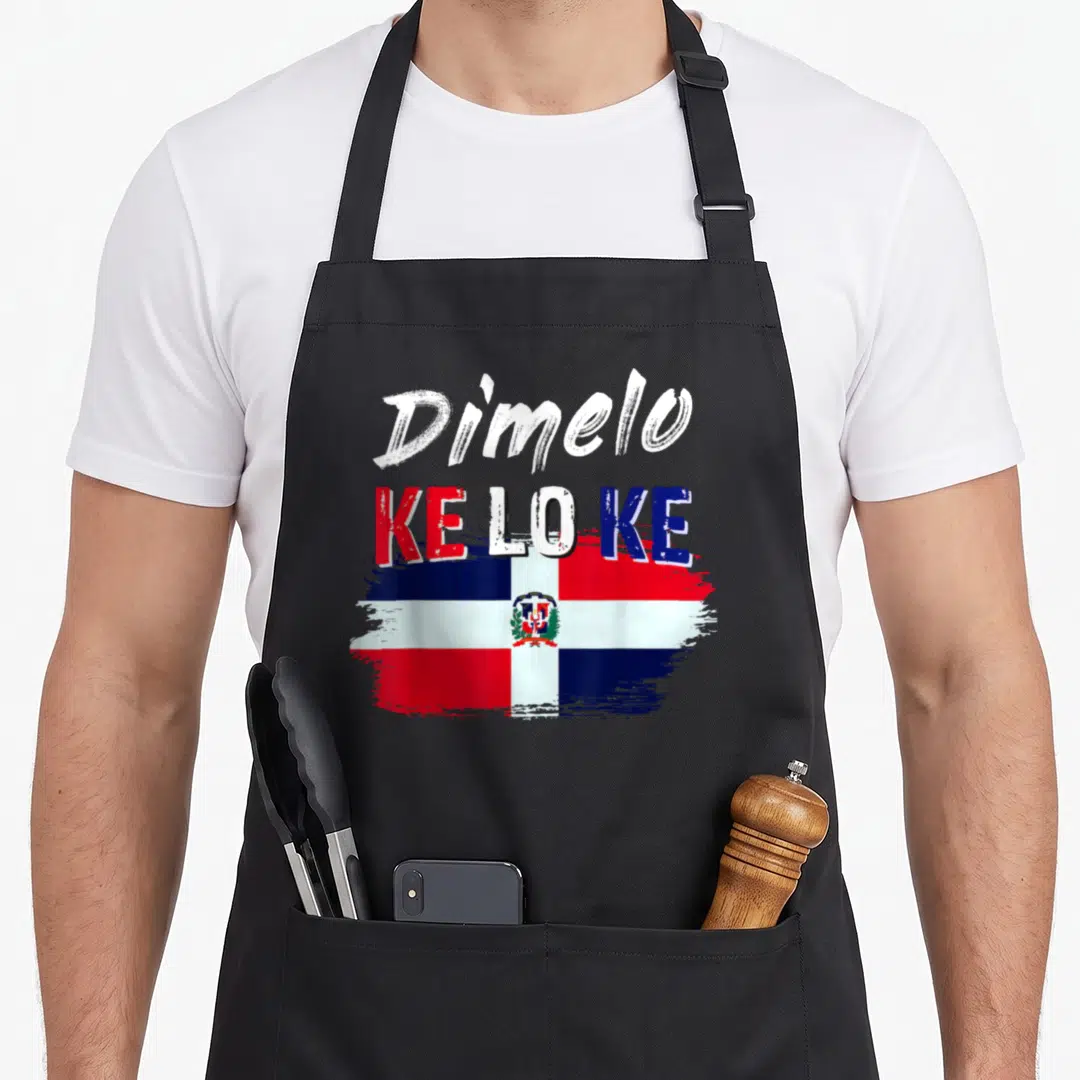 Dimelo dominican apron - Dímelo KE LO KE text over distressed Dominican flag in red white blue — shown on a black cotton canvas apron against a white background
