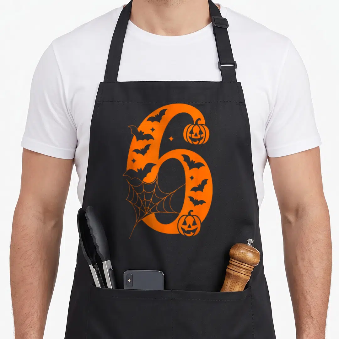 Seven meme halloween apron - Orange number 6 with bat cutouts, spiderweb, and two jack-o-lanterns in cartoon style — shown on a black cotton canvas apron against a white background