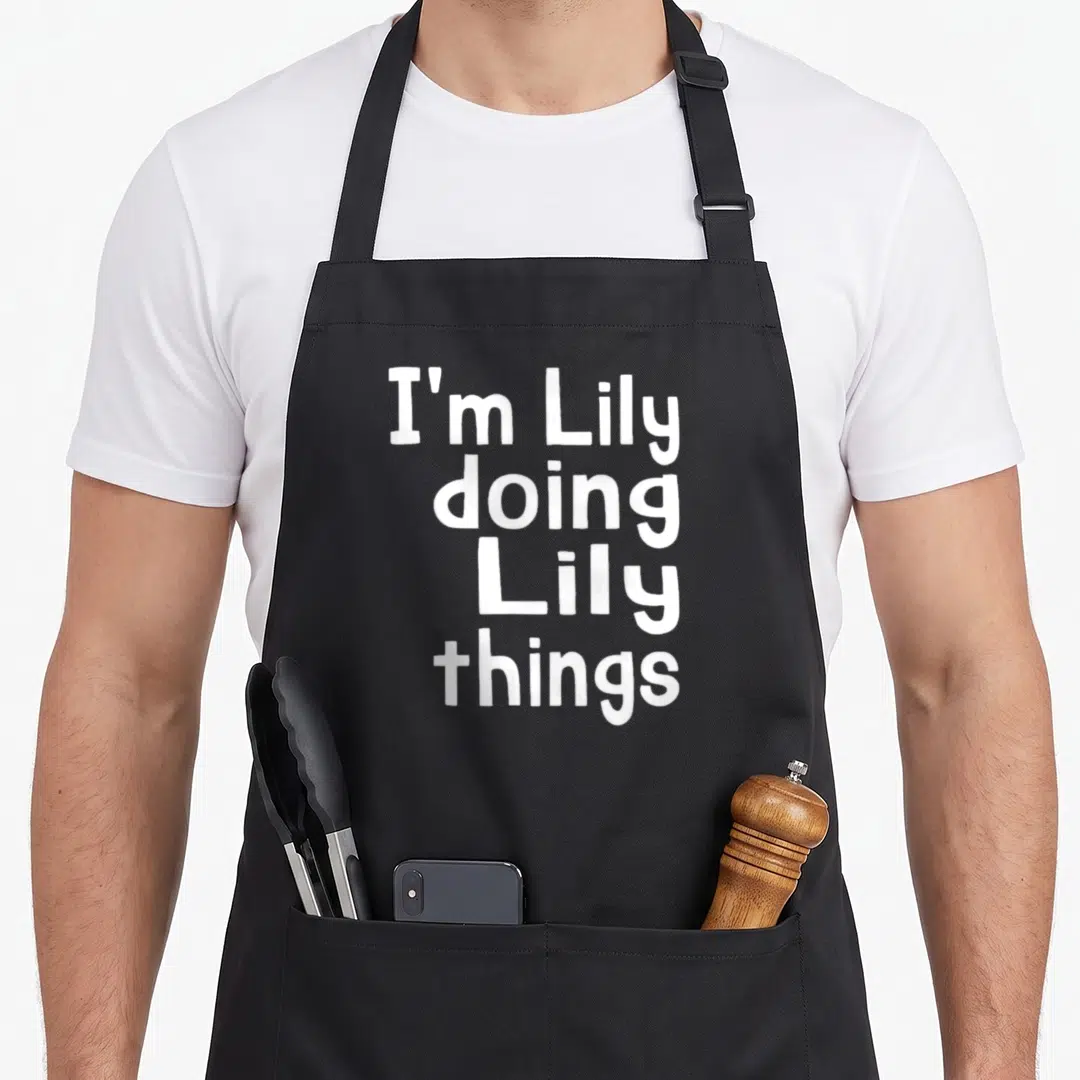 Doing white lily apron - White stacked text reading I'm Lily doing Lily things — shown on a black cotton canvas apron against a white background