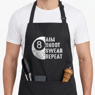Billard father day apron - White distressed half 8-ball next to stacked text AIM SHOOT SWEAR REPEAT — shown on a black cotton canvas apron against a white background