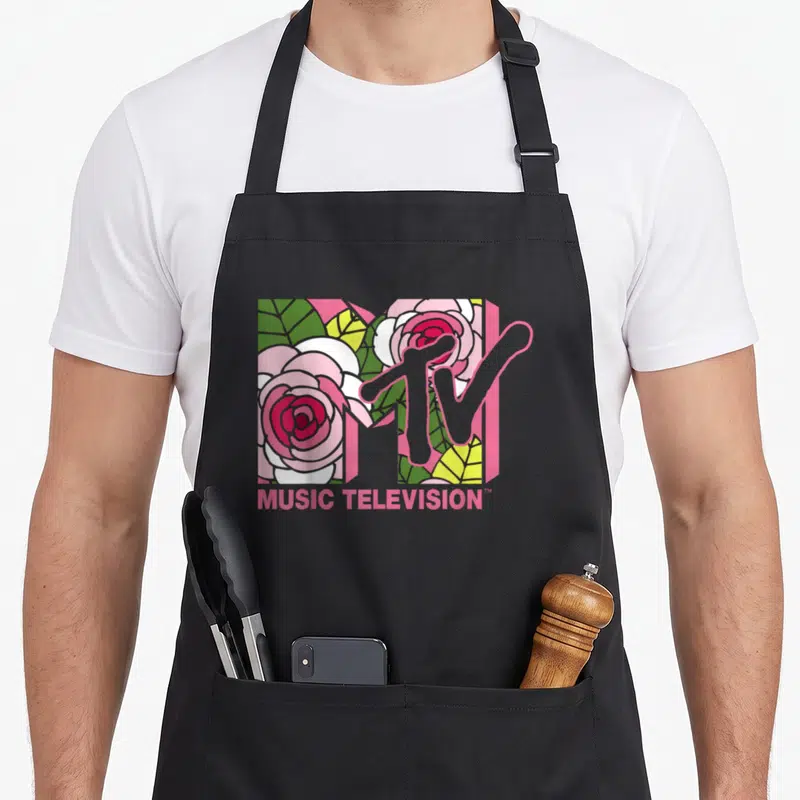 Mtv floral apron - MTV logo with pink roses filling the M and pink MUSIC TELEVISION text below — shown on a black cotton canvas apron against a white background