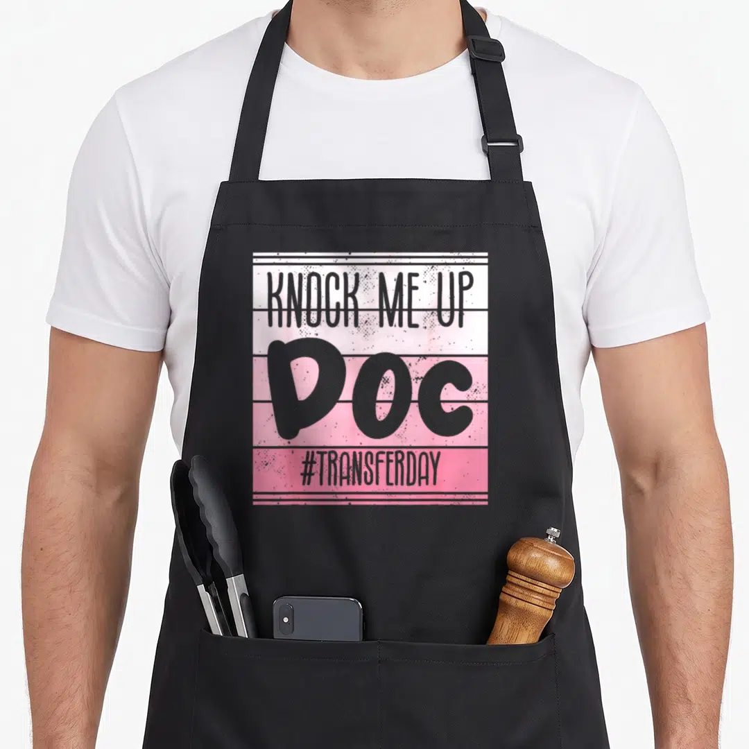 Knock infertility awareness apron - Grey KNOCK ME UP DOC text on pink and white horizontal stripes — shown on a black cotton canvas apron against a white background