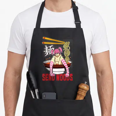 Send anime apron - Anime girl in ramen bowl with SEND NOODS text and kanji characters — shown on a black cotton canvas apron against a white background