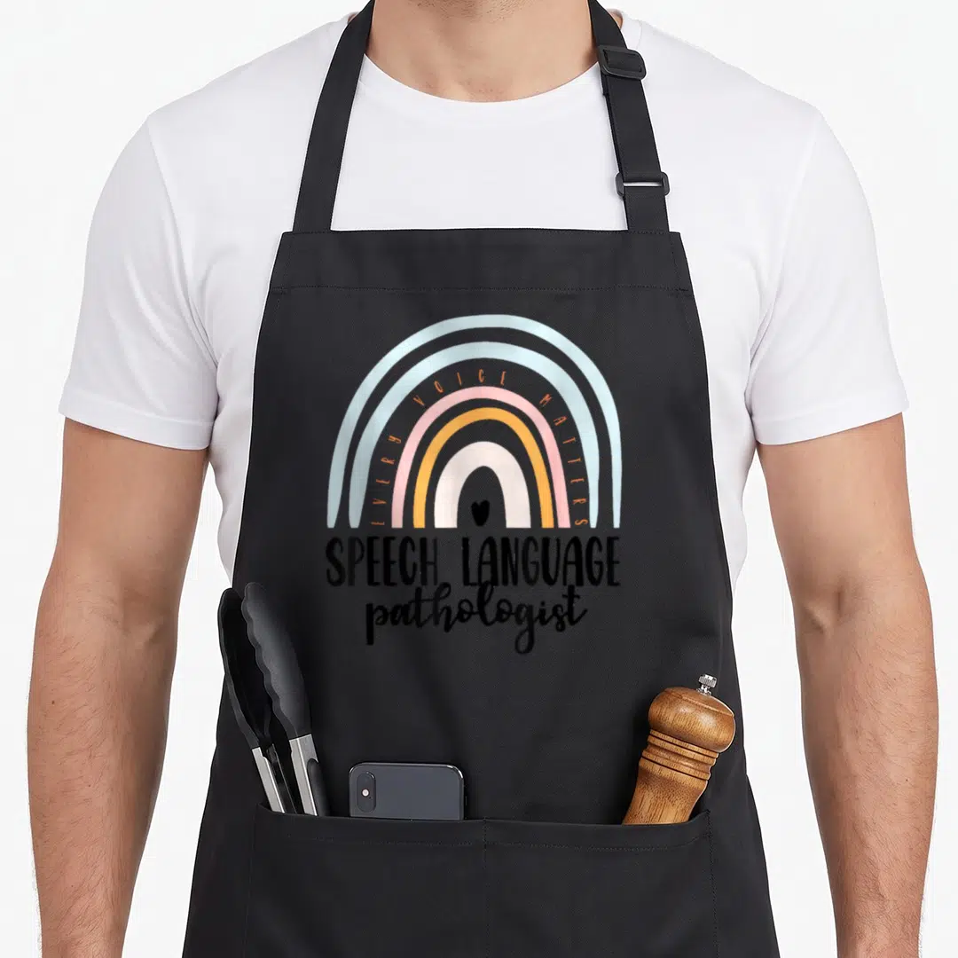 Language boho apron - Rainbow with heart and EVERY VOICE MATTERS text above SPEECH LANGUAGE pathologist lettering — shown on a black cotton canvas apron against a white background