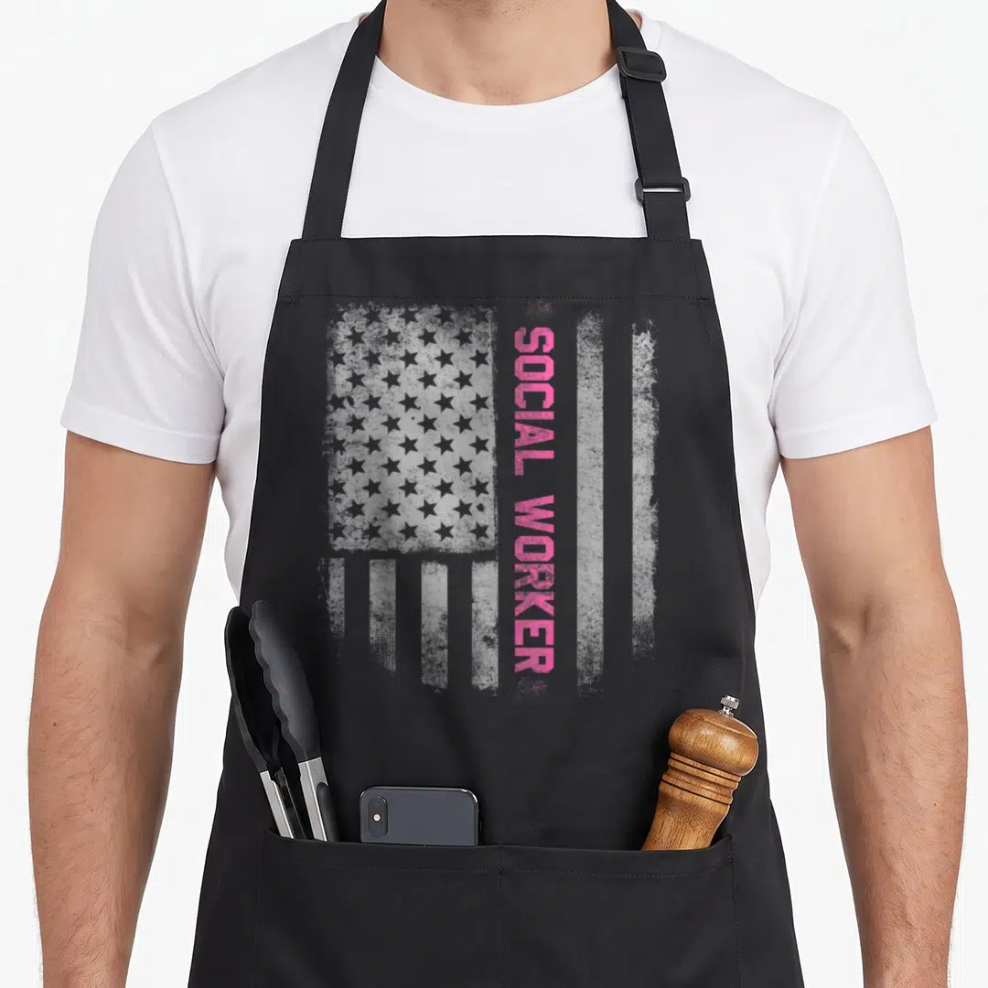 Social us aprons - Distressed grey US flag with vertical pink SOCIAL WORKER text — shown on a black cotton canvas apron against a white background
