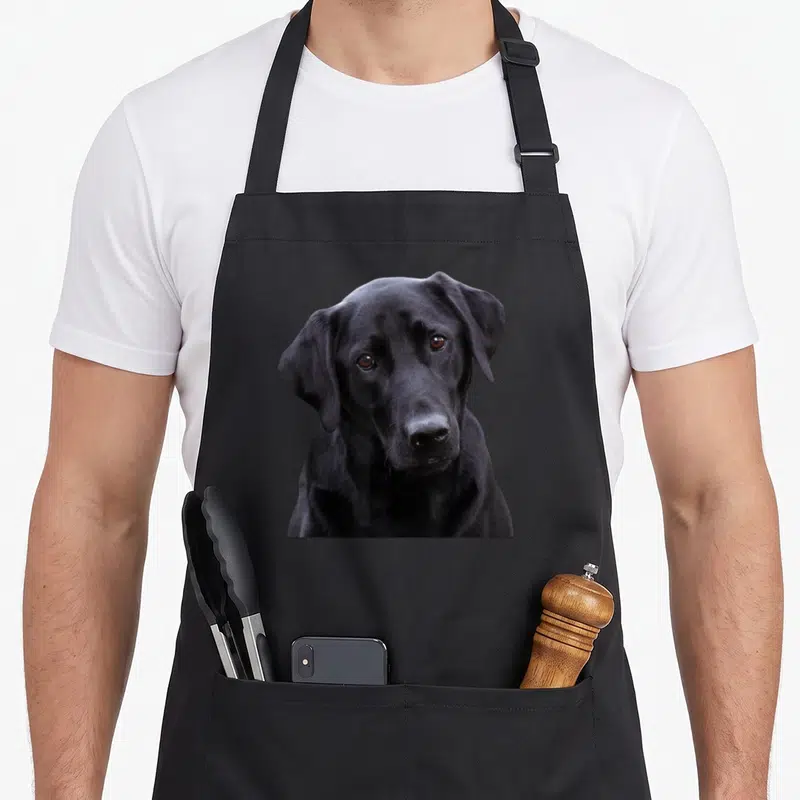 Lab dog labrador apron - Realistic photo of a black Labrador Retriever head centered on a black bib apron — shown on a black cotton canvas apron against a white background