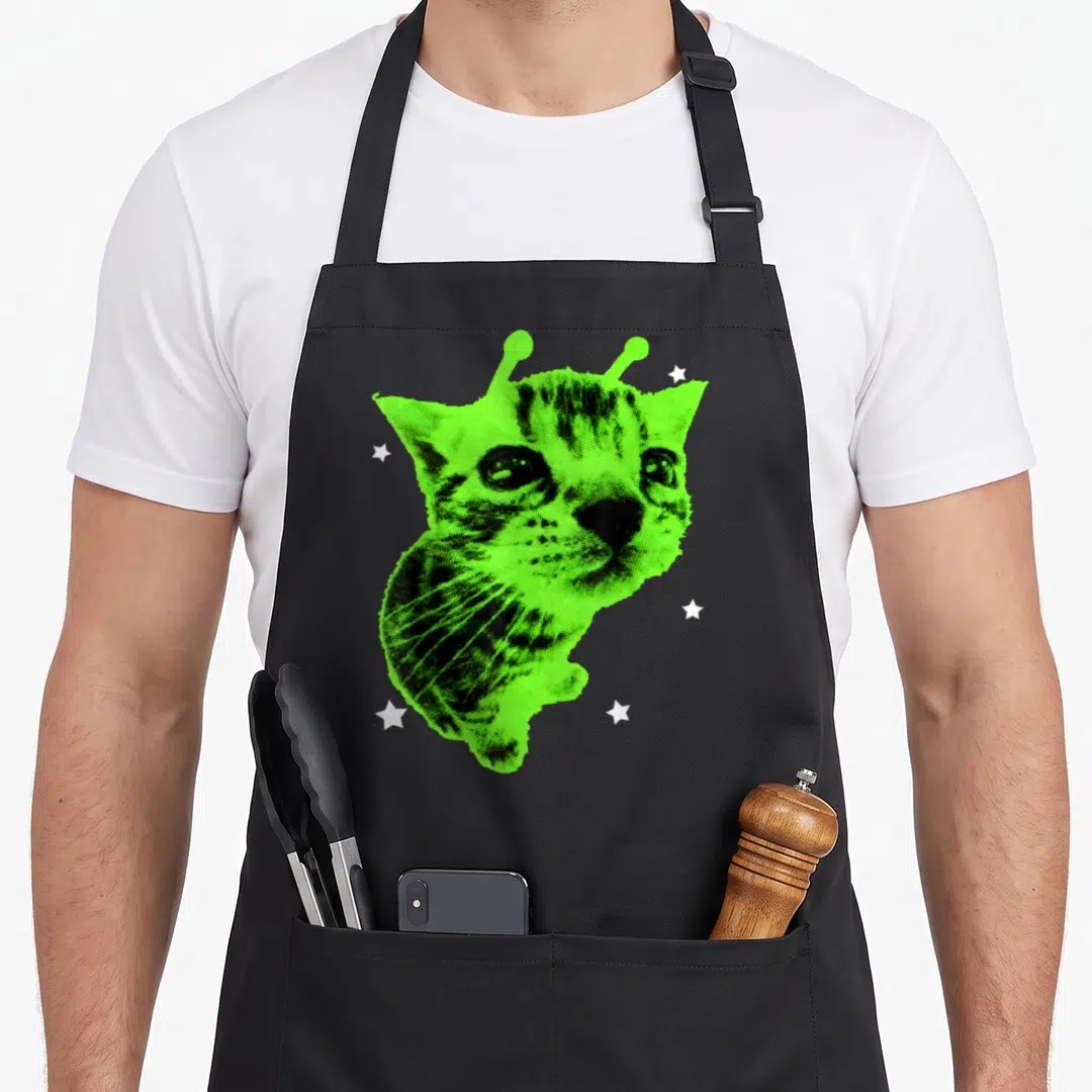 Y2k space cat apron - Lime green distressed cat head with antennae and five white stars — shown on a black cotton canvas apron against a white background