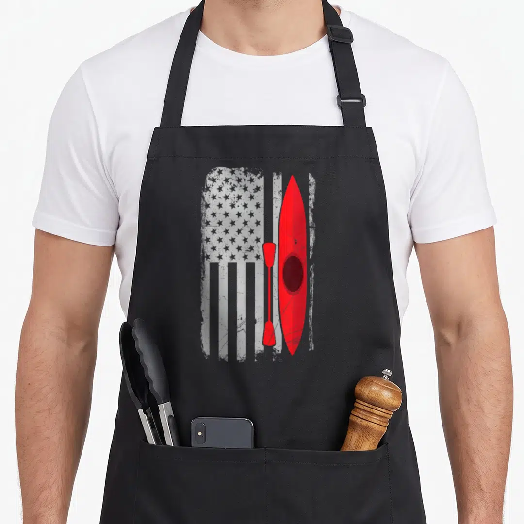 Kayak american flag apron - Red kayak and paddle over distressed grey and white flag pattern — shown on a black cotton canvas apron against a white background