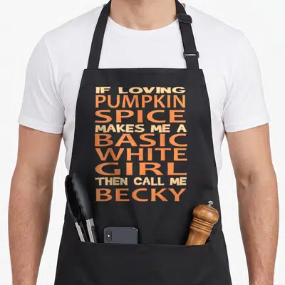 Basic spice apron - Stacked orange and peach text reading If Loving Pumpkin Spice Makes Me A Basic White Girl Then Call — shown on a black cotton canvas apron against a white background
