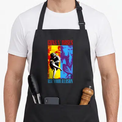 Illusion gun apron - Guns N Roses Use Your Illusion art with two statues in red yellow blue purple — shown on a black cotton canvas apron against a white background