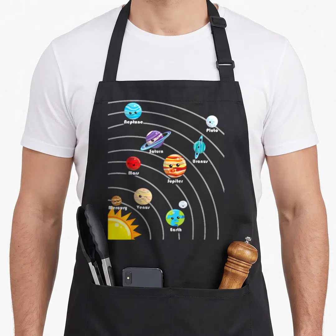 Planet colorful aprons - Cartoon solar system with labeled planets Mercury through Pluto and a yellow sun on white — shown on a black cotton canvas apron against a white background