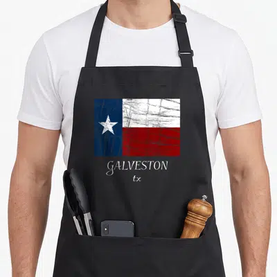 Galveston texas flag apron - Distressed Texas flag in blue white red above GALVESTON tx text — shown on a black cotton canvas apron against a white background