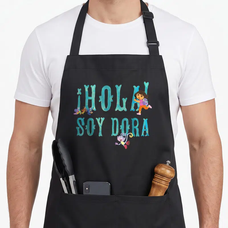 Hola explorer apron - Teal ¡HOLA SOY DORA text with jumping girl and musical snail characters — shown on a black cotton canvas apron against a white background
