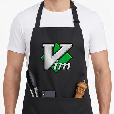 Vim editor apron - White Vim text with black outline overlapping a green 3D diamond shape — shown on a black cotton canvas apron against a white background