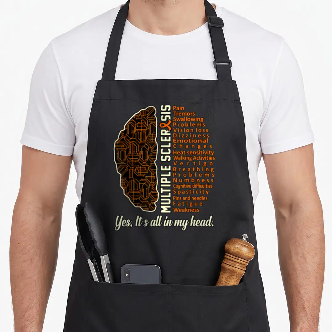 Fact multiple sclerosis awareness apron - Brain silhouette with orange circuitry and vertical symptom list reading Yes — shown on a black cotton canvas apron against a white background