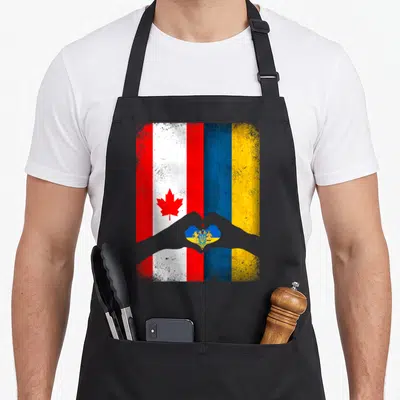 Canadian ukrainian aprons - Grey hands making heart shape over red white blue and yellow distressed flags — shown on a black cotton canvas apron against a white background