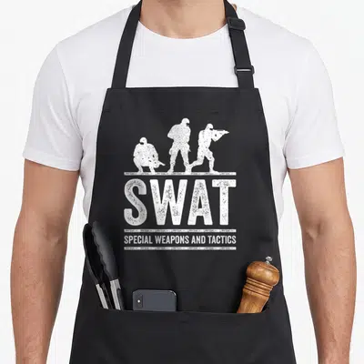 Duty swat bbq apron - Three white distressed officer silhouettes above large SWAT text and bottom tagline — shown on a black cotton canvas apron against a white background