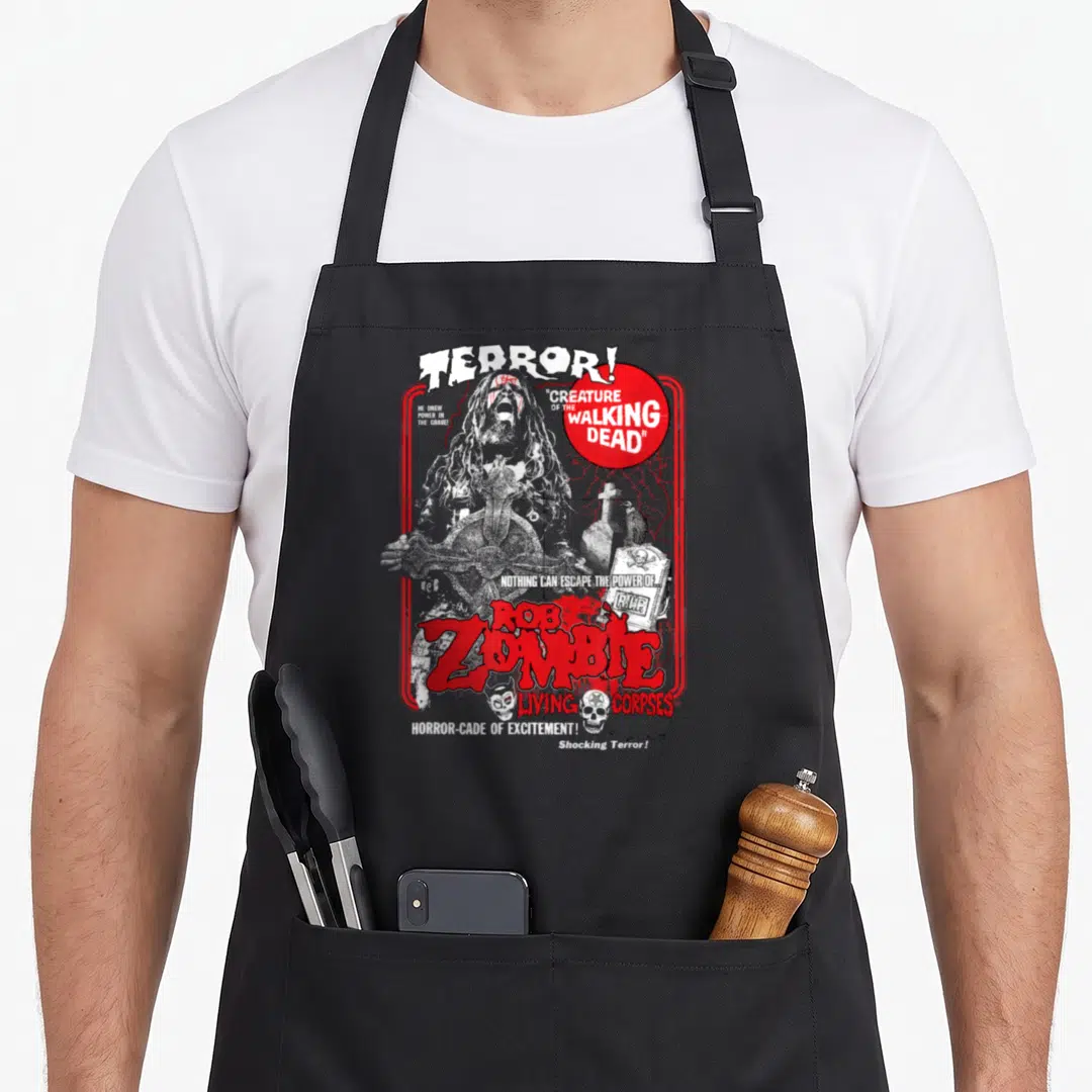 Rob pull girl apron - Distressed zombie graphic with red circle, crow on tombstone, skulls, and horror text — shown on a black cotton canvas apron against a white background