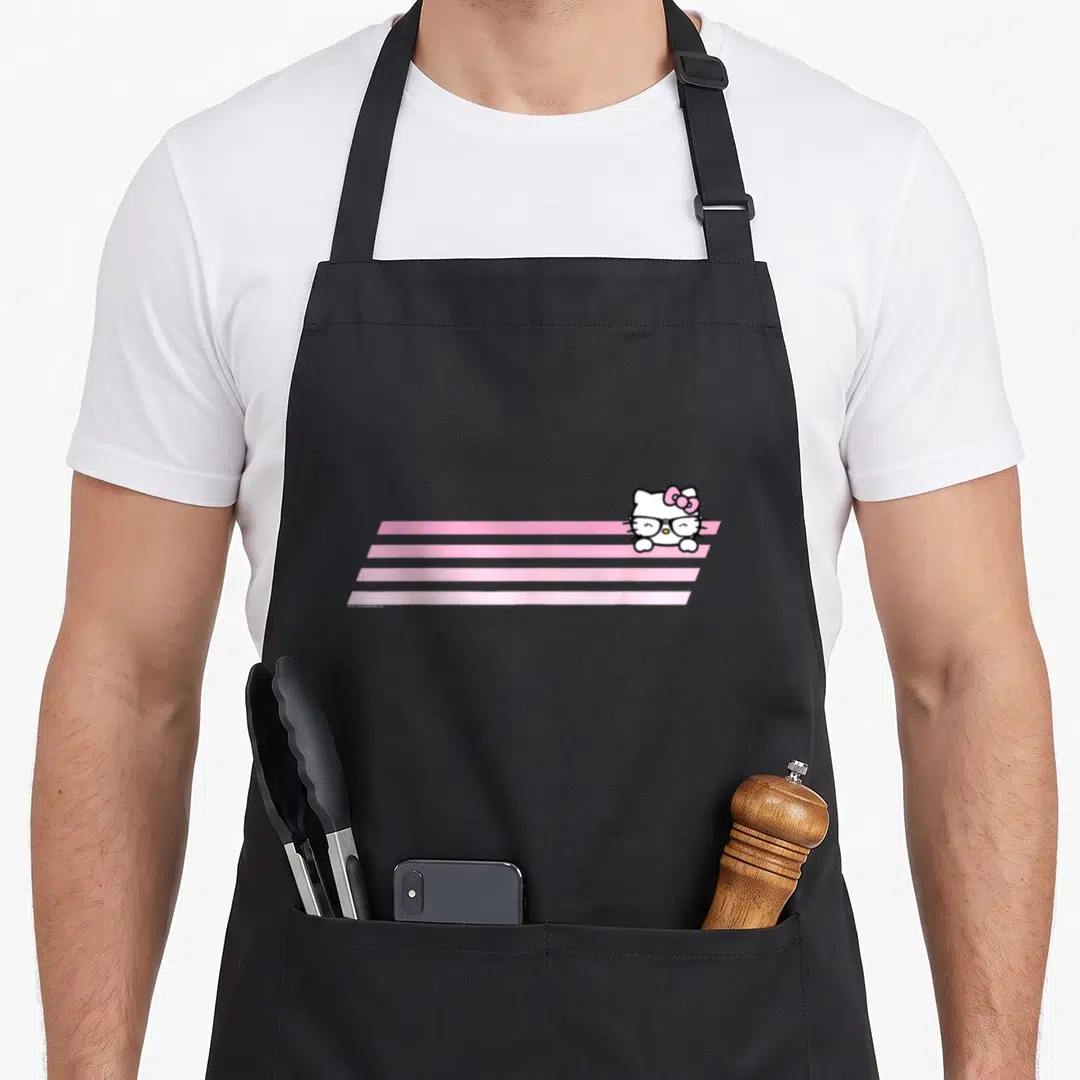 Stripe nerd apron - Hello Kitty sitting on four pink stripes with white, pink, black cartoon art — shown on a black cotton canvas apron against a white background