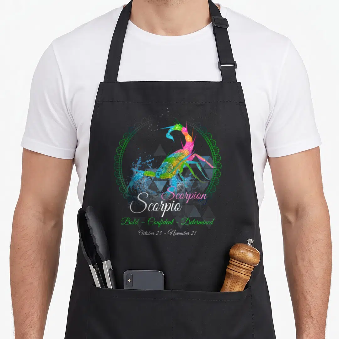 Scorpion birthday apron - Rainbow scorpion in blue, green, pink, yellow with Scorpio text and green circular border — shown on a black cotton canvas apron against a white background