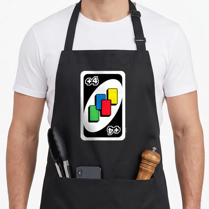 Uno draw an apron - +4 card with four colored rectangles and corner text — shown on a black cotton canvas apron against a white background