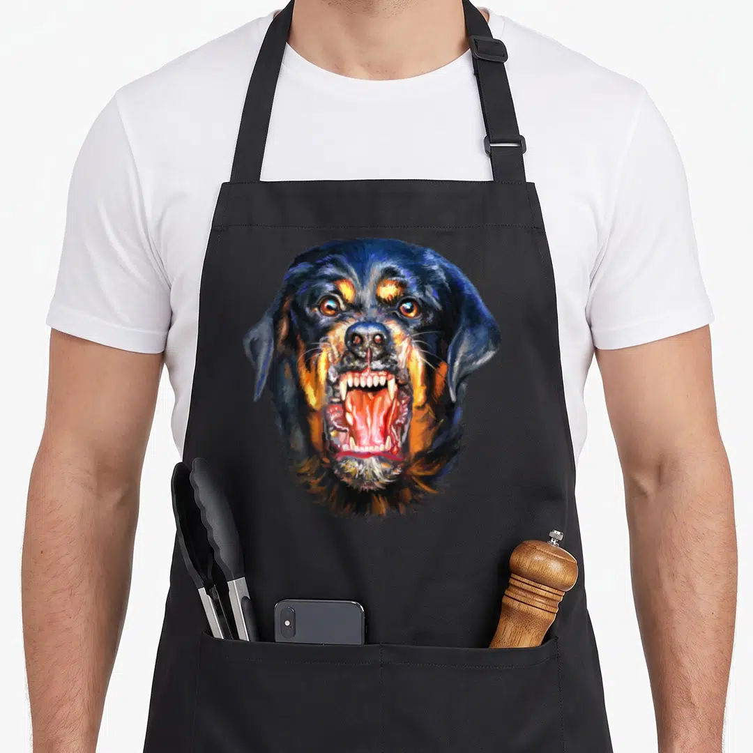Angry dog apron - Realistic painting of a barking Rottweiler head in black, tan, and red — shown on a black cotton canvas apron against a white background