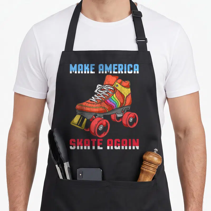 Roller 80s apron - Distressed quad skate graphic with MAKE AMERICA SKATE AGAIN text in red and blue block letters — shown on a black cotton canvas apron against a white background