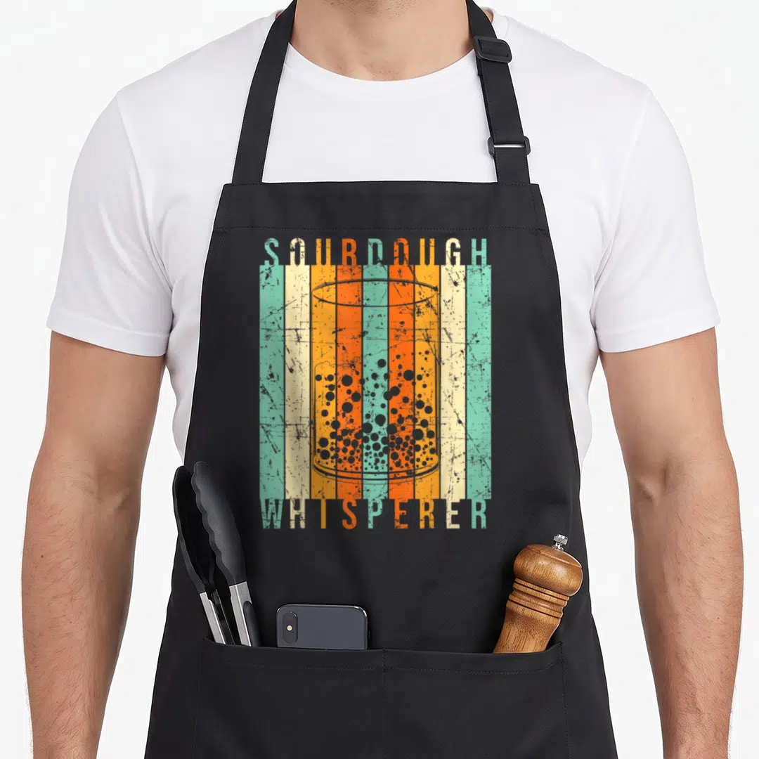 Sourdough bread apron - Retro jar with bubbles and SOURDOUGH WHISPERER text on teal and orange stripes — shown on a black cotton canvas apron against a white background