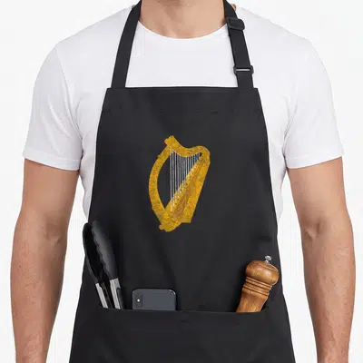 Harp flag ireland apron - Gold line art harp illustration on stiff cotton canvas with split pockets — shown on a black cotton canvas apron against a white background