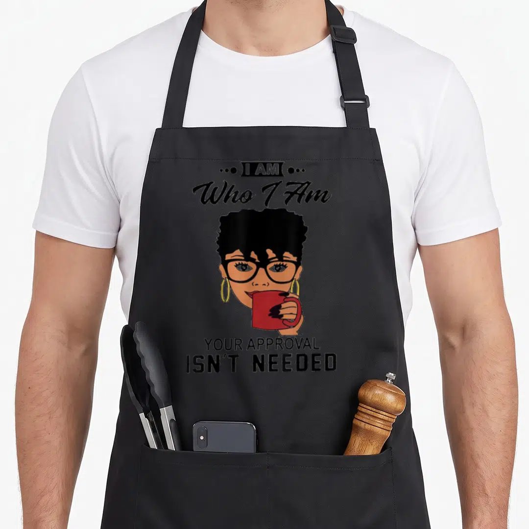 Approval coffee aprons - Cartoon woman with glasses holding red mug with text I AM Who I Am YOUR APPROVAL ISN'T NEEDED — shown on a black cotton canvas apron against a white background