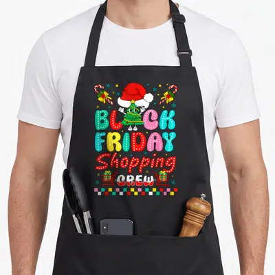 Christmas light black friday apron - Cartoon Christmas tree wearing a Santa hat above colorful BLACK FRIDAY Shopping — shown on a black cotton canvas apron against a white background