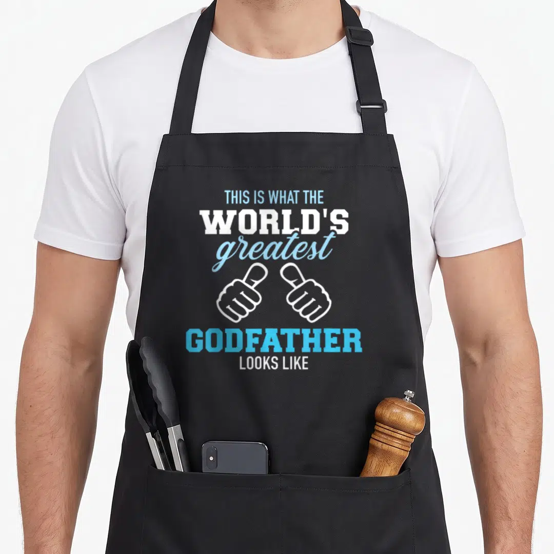 Godfather worlds greatest dad apron - Stacked blue and white text reading This Is What The World's Greatest Godfather — shown on a black cotton canvas apron against a white background