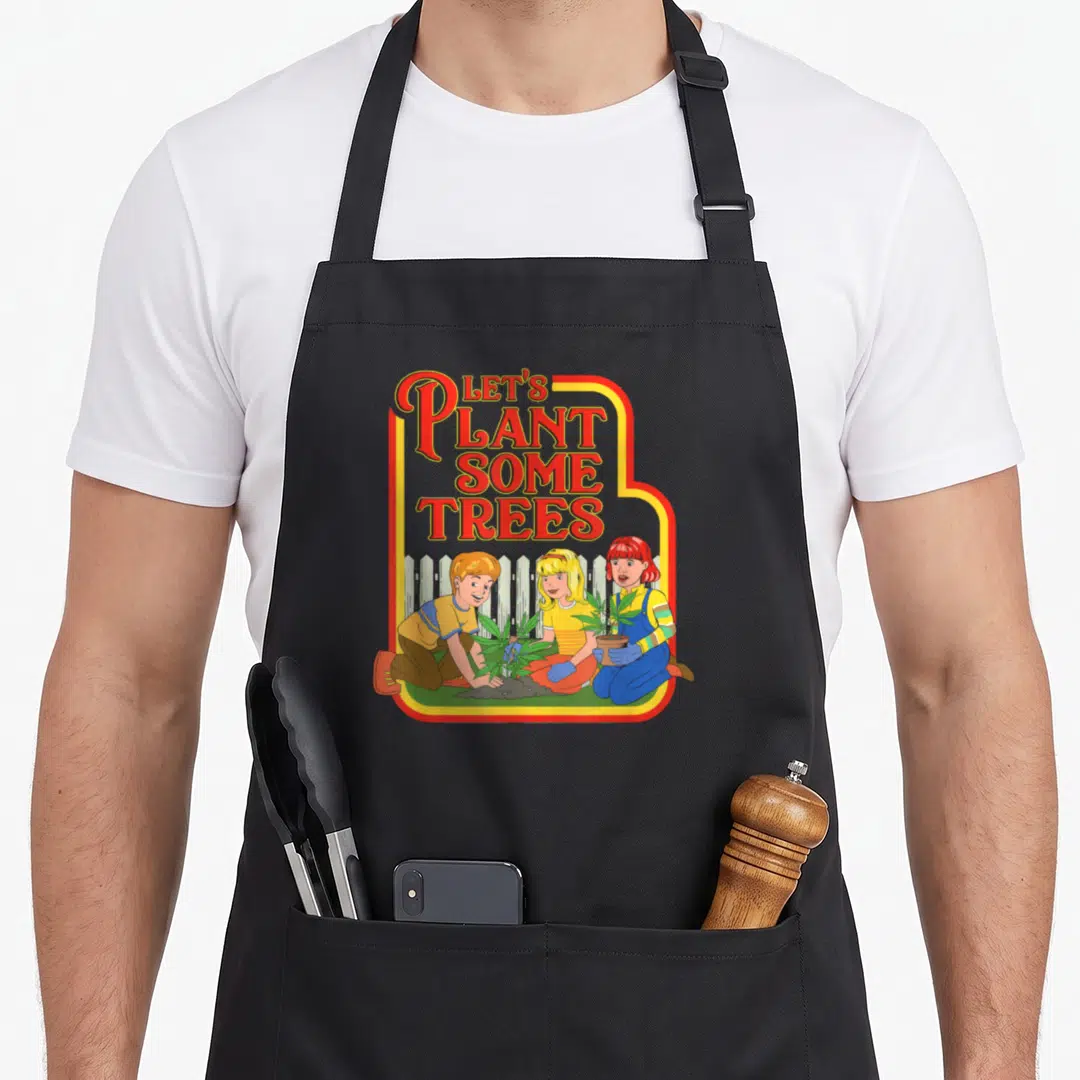 Plant tree apron - Red text Let's Plant Some Trees above three kids planting green leafy plants in front of white fence — shown on a black cotton canvas apron against a white background