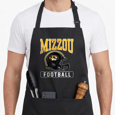 Missouri football apron - Arched MIZZOU text above black helmet with tiger head and white FOOTBALL label — shown on a black cotton canvas apron against a white background