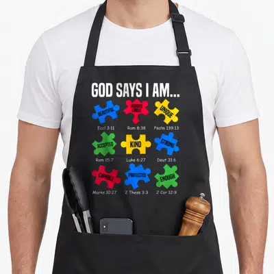 Awareness god says i am apron - Colored puzzle pieces with words BEAUTIFUL STRONG ENOUGH and scripture references — shown on a black cotton canvas apron against a white background