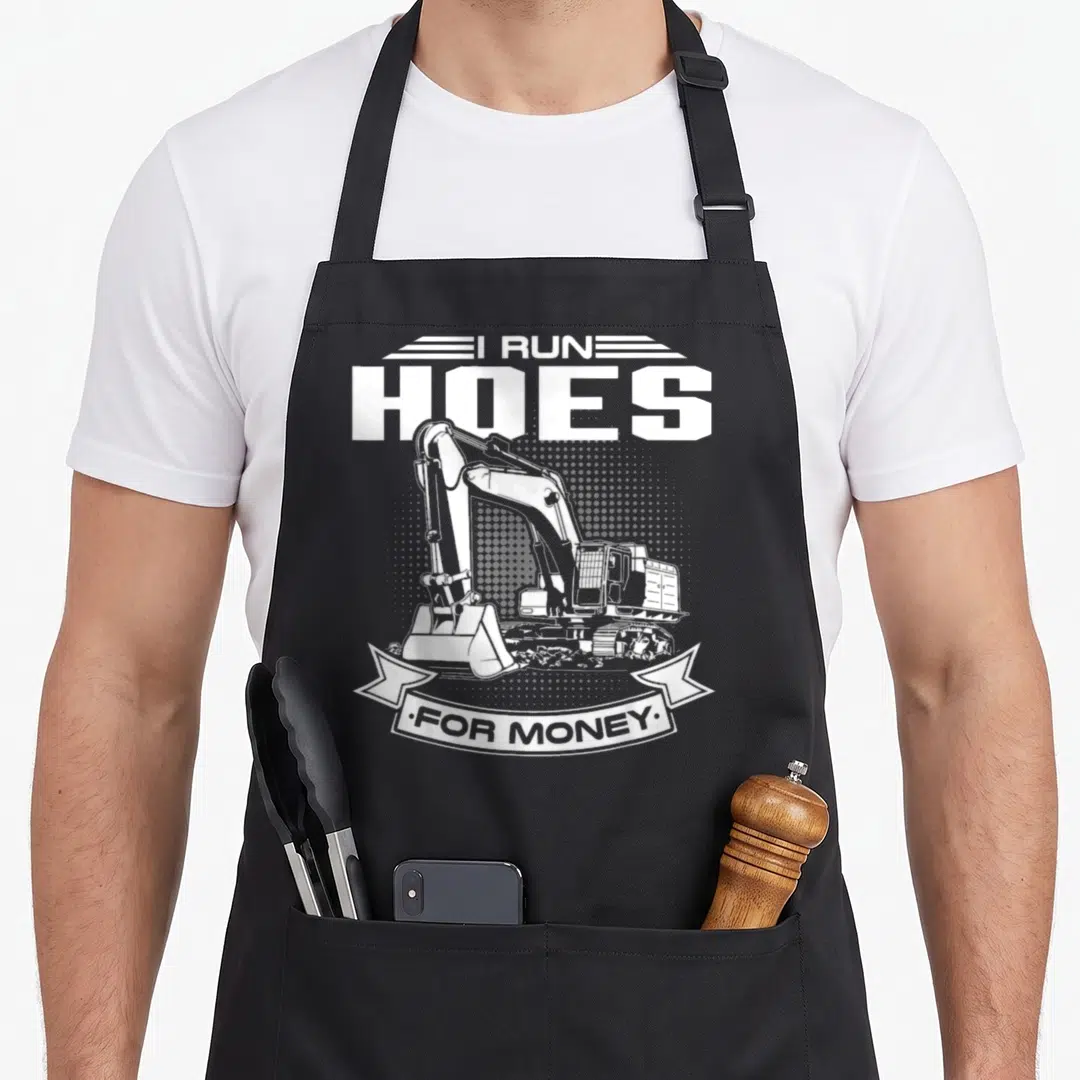 Run construction worker apron - White excavator graphic with I RUN HOES FOR MONEY text in retro style — shown on a black cotton canvas apron against a white background