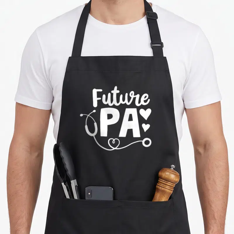 Future assistant doctor apron - White Future PA text with stethoscope and three hearts on grey background — shown on a black cotton canvas apron against a white background