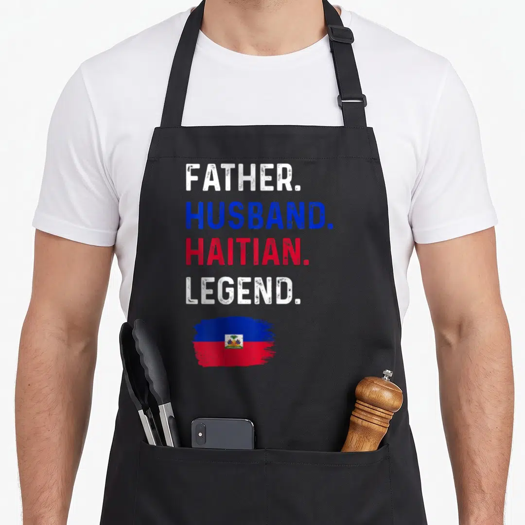 Haitian husband apron - Stacked text reading Father Husband Haitian Legend above a blue and red brush stroke flag — shown on a black cotton canvas apron against a white background