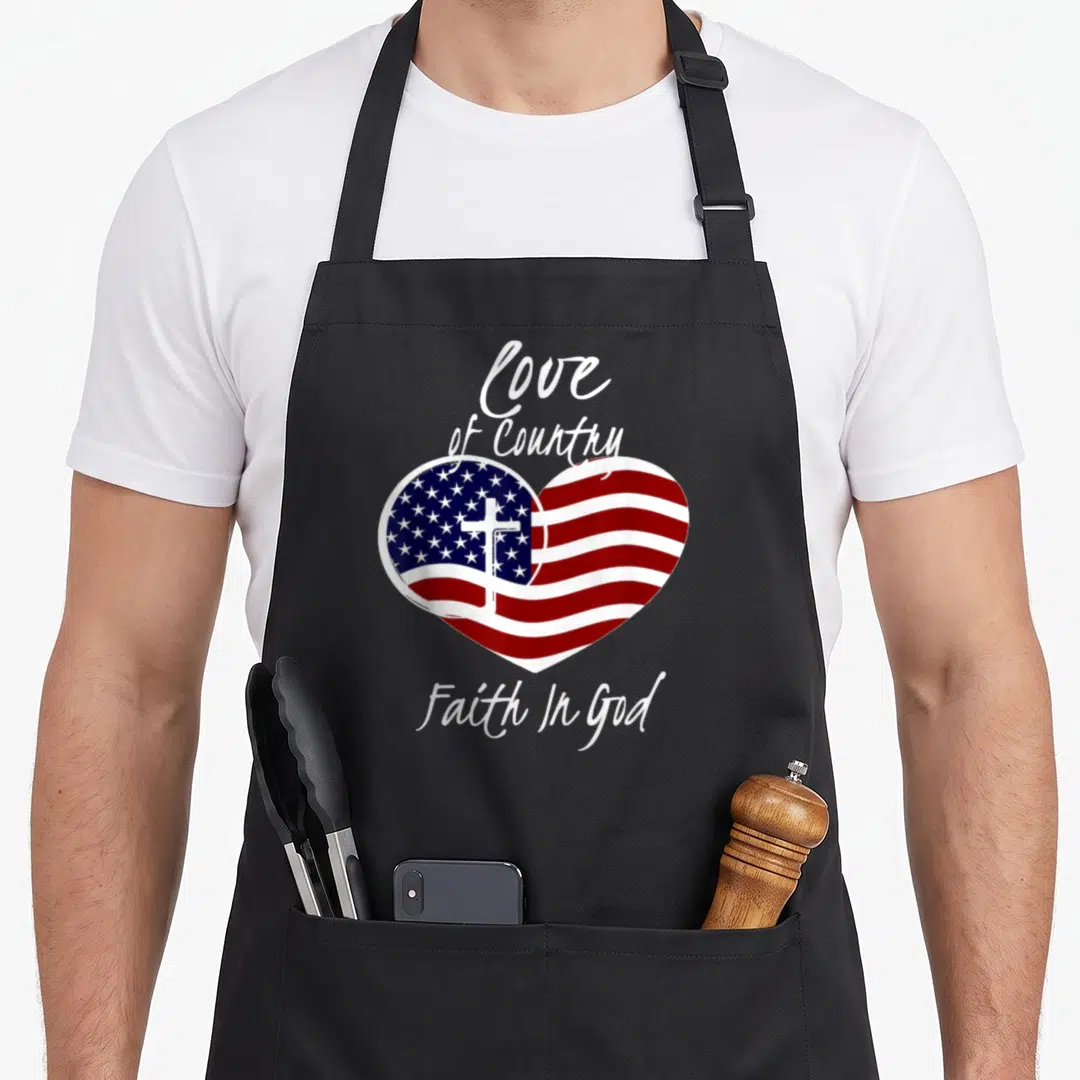 Patriotic christian aprons - Heart filled with flag and cross, text Love of Country Faith In God — shown on a black cotton canvas apron against a white background