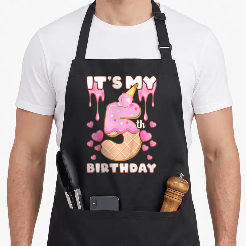 5th ice cream apron - Pink number 5 ice cream cone with IT'S MY BIRTHDAY text and scattered hearts — shown on a black cotton canvas apron against a white background