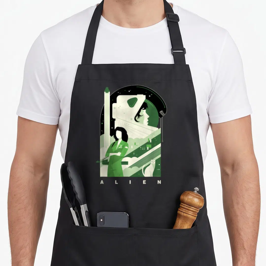 Anniversary 20th century studios apron - Green and black graphic of woman, helmet profile, cat, and ALIEN text — shown on a black cotton canvas apron against a white background